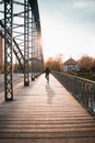 Young tourist with a backpack walking alone on a wooden bridge during the sunset Royalty Free Stock Photo