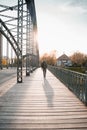 Young tourist with a backpack walking alone on a wooden bridge during the sunset Royalty Free Stock Photo