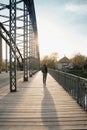 Young tourist with a backpack walking alone on a wooden bridge during the sunset Royalty Free Stock Photo