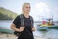 Young tourist of a blonde girl with backpack on the beach with pleasure looking at a beautiful sea landscape Royalty Free Stock Photo