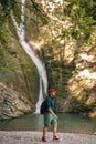 Young tourist camping with backpack near a waterfall in forest. Royalty Free Stock Photo