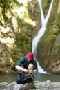 Young tourist camping with backpack near a waterfall in forest. Royalty Free Stock Photo