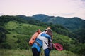 Young tourist couple travellers with backpacks hiking in nature, hugging. Royalty Free Stock Photo