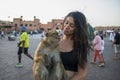 Young tourist enjoying and caressing a monkey in Jemaa el Fna square in Marrakech in Morocco Royalty Free Stock Photo