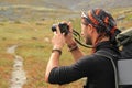 Young tourist guy unshaven, in a hat and with baubles on his hands and a backpack on his shoulders makes a photo