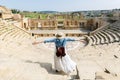 Young tourist with hat and open arms in Antique Theatre. In ancient Roman city of Jerash, Jordan