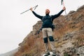 Young tourist male hiking in mountains, finished his track, feels happy. Traveler bearded man mountaineering during his journey Royalty Free Stock Photo