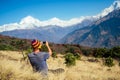 A young tourist man with a hiking backpack and a knitted cap taking pictures of the landscapes and making selfi in the Royalty Free Stock Photo