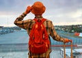 Happy time with young tourist man holding the luggage and he is watching the flight and sunset through window in airport terminal