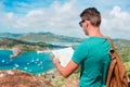 Young tourist man with map background of English Harbor from Shirley Heights, Antigua