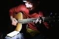 Young tourist man playing guitar, singing and using phone app with chords and song lyrics. Guitarist traveler