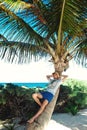 Young tourist man relaxing on palm tree on the caribbean beach. Vacation Royalty Free Stock Photo