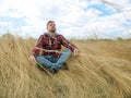 Young tourist sits in the grass on autumn field. Relaxation and Meditation.