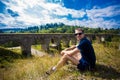 Young tourist sitting on green hill outdoor near old stone railway bridge Royalty Free Stock Photo