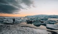 Young tourist standing in front of famous lake Joekulsarlon glacial lagoon and diamond beach with its icebergs and ice