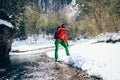 Young tourist throws snow near a river in the mountains..