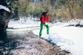 Young tourist throws snow near a river in the mountains