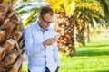 Young tourist under palm tree with mobile phone and tablet. Nega Royalty Free Stock Photo