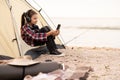 Young tourist on vacation in seashore. Happy teen girl relaxing in camping tent. Hiker child listen to music from the Royalty Free Stock Photo