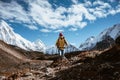 Young tourist walk along high altitude track among snowy and cloudy mountains. Man expeditor with travel backpack going across Royalty Free Stock Photo