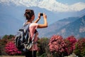 A young tourist woman with a camp backpack photographing landscapes and making selfi in the Himalaya Mountains. trekking Royalty Free Stock Photo