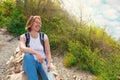 A young tourist woman climbed the mountain , and at the top decided to relax a little. Plants and sky with clouds on the