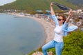 A young tourist woman climbed to the top of the mountain. Emotions of joy and happiness. Mountain and sea in the background. Close