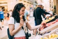 Young tourist woman eating an ice cream and buying some fruit in a street market Royalty Free Stock Photo