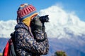 A young tourist woman with a hiking backpack and a knitted hat photographing landscapes in the Himalaya Mountains Royalty Free Stock Photo