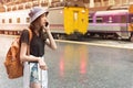 Young tourist woman holding cellphone and call Find accommodation on railway station. Travel concept
