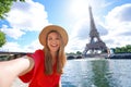 Young tourist woman making selfie photo with Eiffel tower on the background in sunny day in Paris, France Royalty Free Stock Photo