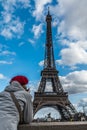 Young tourist woman with Parisian style red hat looking at Eiffel tower from the Seine river side. France