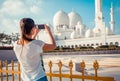 Young tourist woman shooting on mobile phone Sheikh Zayed great white mosque in Abu Dhabi, United Arab Emirates, Persian gulf. UAE Royalty Free Stock Photo