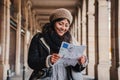 Young tourist woman smiling and reading a map to find the location of the european monument. Lost traveler female