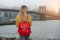 Young tourist woman traveling in New New York city with red backpack and looking to Brooklyn Bridge Royalty Free Stock Photo