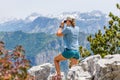 Young tourist woman watching birds in the mountains. Slim hiker birdwatcher girl with binoculars