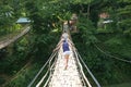 Young tourists cross the scary hand crafted bamboo bridge