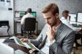 The Right Way of Trading. Young trader sitting by desk and looking seriously at analytical reports while working in the