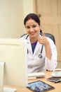 Young traditional female doctor making thumbs up gesture