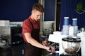 Professional coffee brewing. Young trained barista preparing coffee on professional steam coffee machine