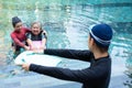 Young trainer helping senior woman in aqua aerobics and working out in the pool. old woman and mature man doing aqua aerobics Royalty Free Stock Photo