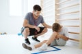 Young trainer helps the injured boy at the school gym