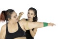 Young trainer measuring bicep of fat woman