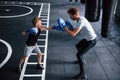 Young trainer teaches kid boxing sport in the gym