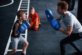 Young trainer teaches kids boxing sport in the gym