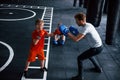 Young trainer teaches kids boxing sport in the gym