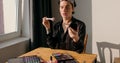 Young transgenger queer man puts on make up , beauty routine sitting at table.