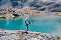 Young travel girl staying on top of high rock cape near mountains lake.