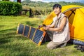 Young travel man relax and enjoy camping . Hand male plug in portable solar panel charging smartphone by multipurpose cable, Clean