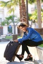 Young travel woman sitting outside with suitcase